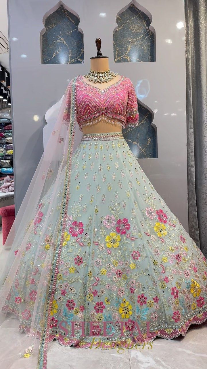 a dress on display in front of a window with an elaborate veil and flowered skirt