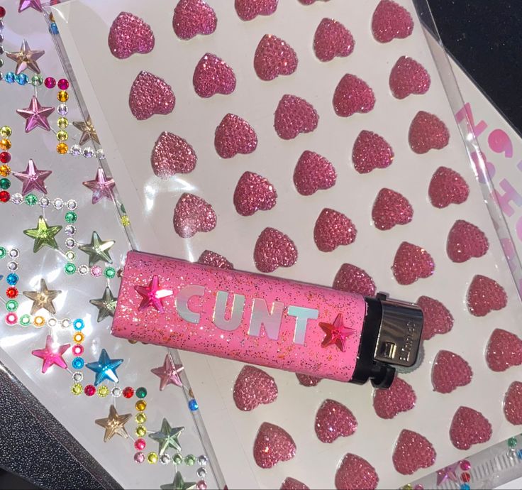 a pink liquid bottle sitting on top of a white table covered in stars and confetti