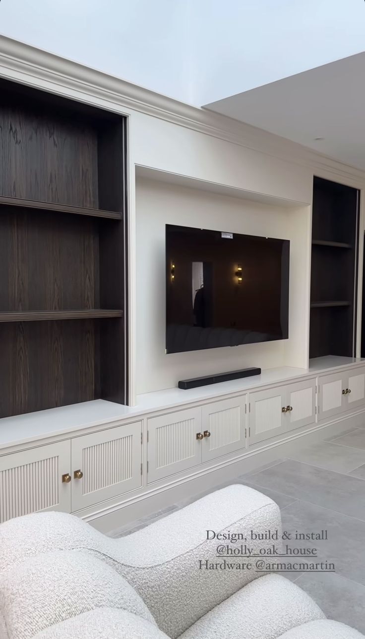 a living room filled with white furniture and a flat screen tv mounted on the wall