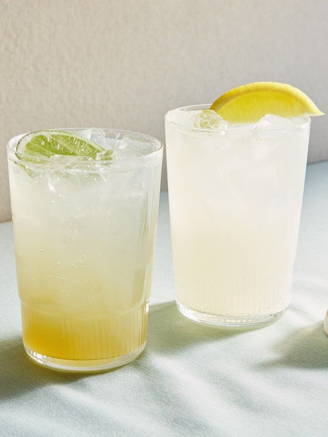 two glasses filled with lemonade and lime on a table