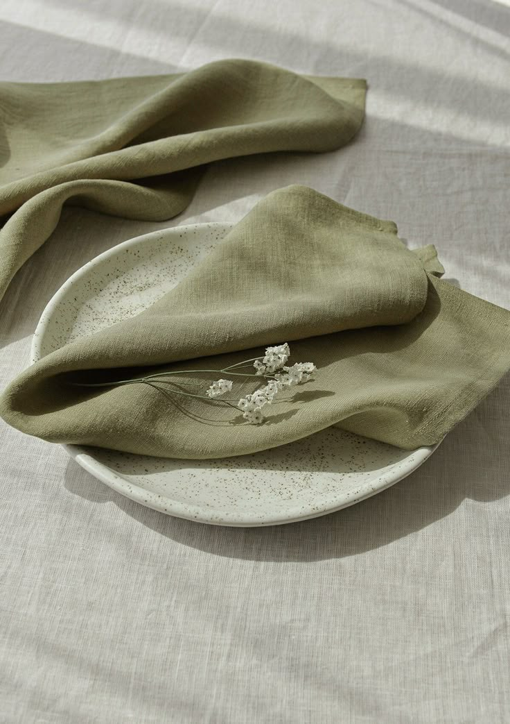 a white plate topped with green napkins on top of a tablecloth covered table