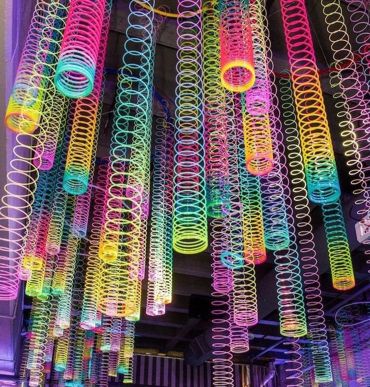 many colorful lights hanging from the ceiling in a building