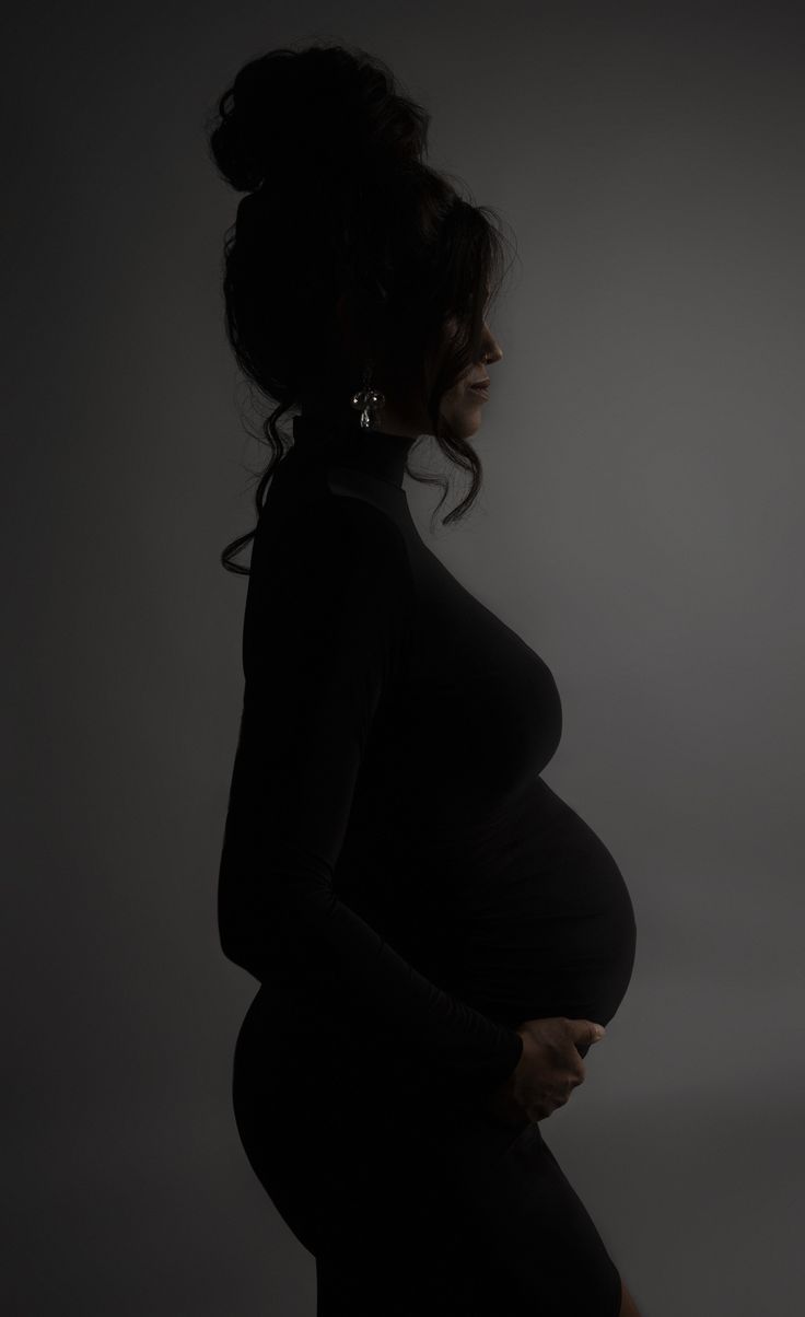 a pregnant woman is standing in the dark