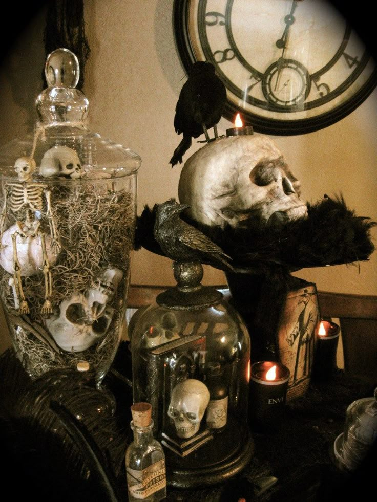 a table topped with skulls and candles next to a clock