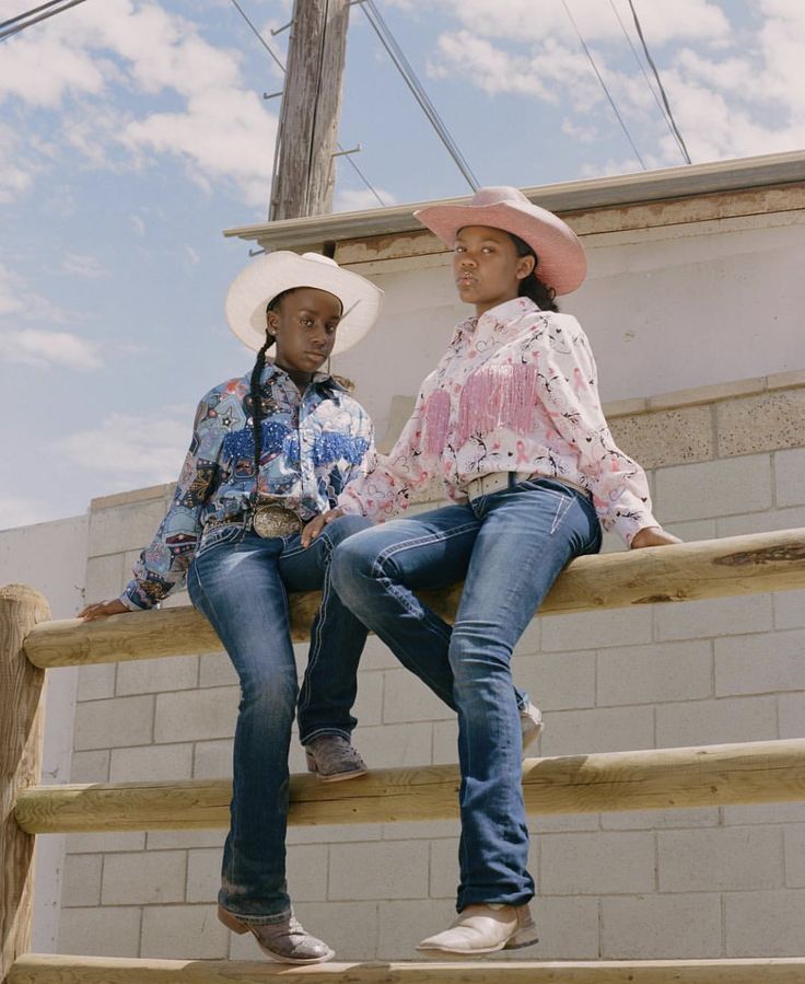 two women in cowboy hats sitting on steps