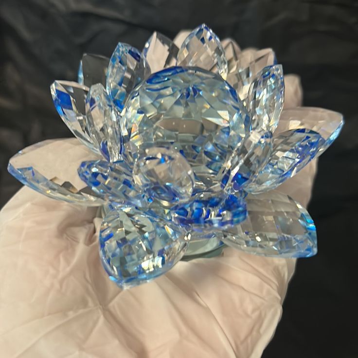 a close up of a blue flower made out of crystal stones on a gloved hand