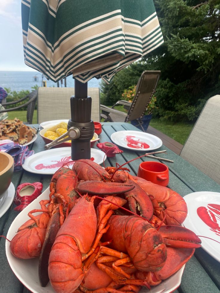 lobsters are on the table ready to be eaten at an outdoor dining area overlooking the ocean