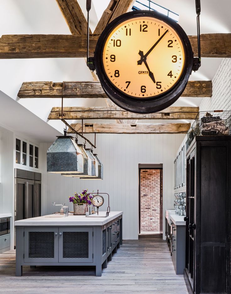 a large clock hanging from the ceiling in a kitchen