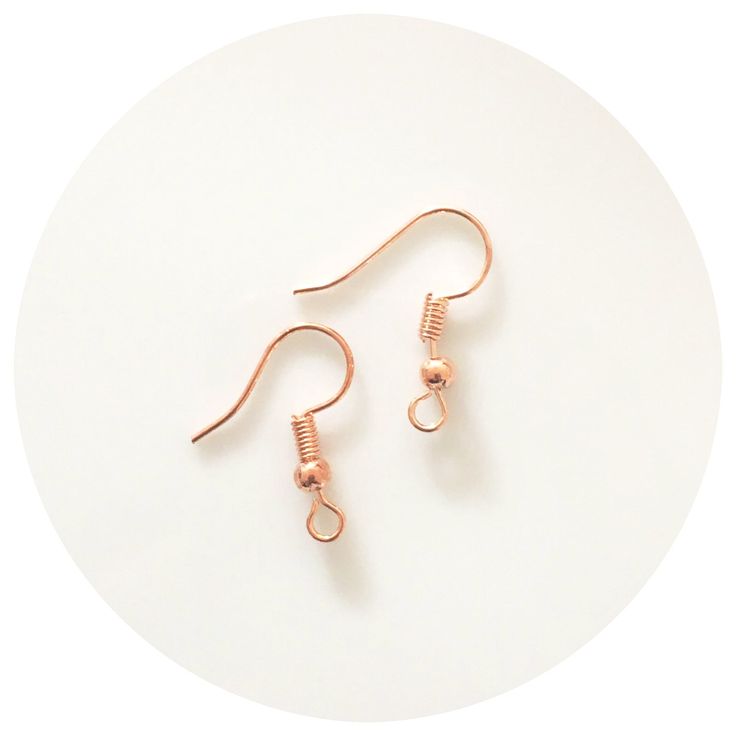 two pairs of copper earrings sitting on top of a white plate