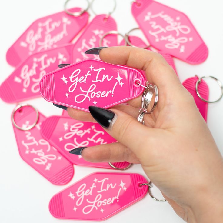 a hand holding a pink keychain with the words get in here written on it