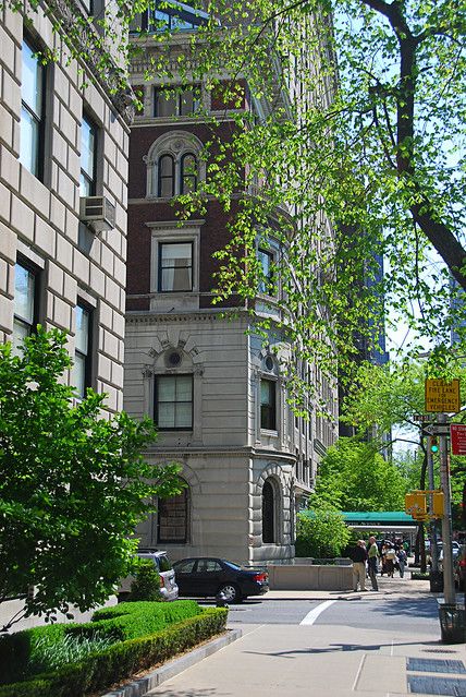 a tall building sitting on the side of a street next to a lush green tree