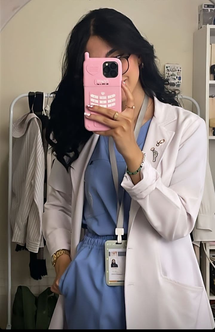 a woman in a lab coat holding up a pink cell phone