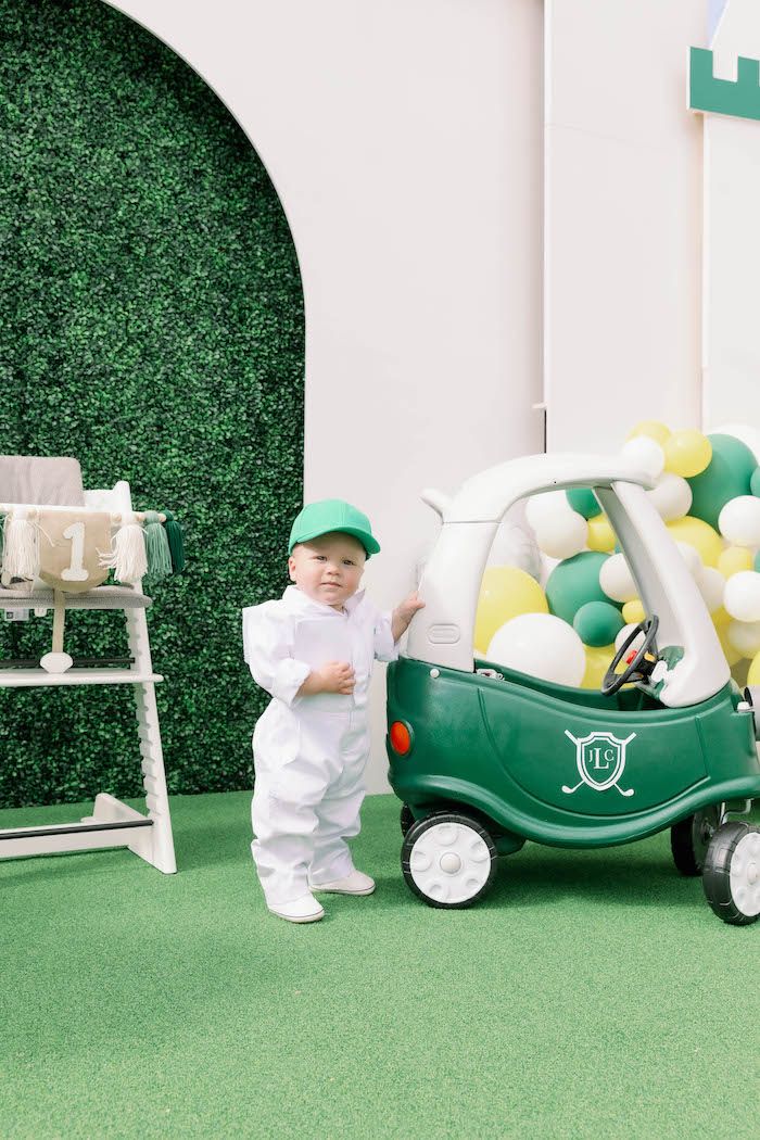 a little boy standing next to a green car