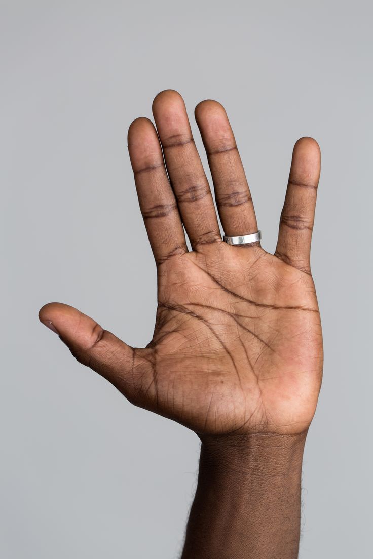 a man's hand with his fingers extended out to the side, holding something up in the air