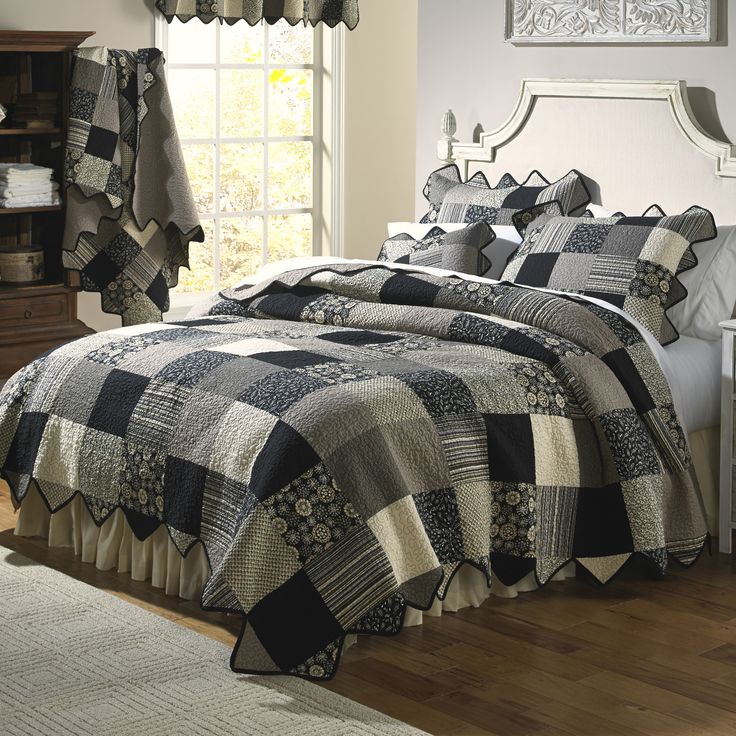 a bed in a bedroom with black and white quilts