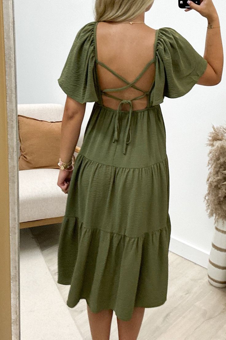 Flaunt your unique style in the "Enchanting You" Midi Dress. This playful olive green dress features flounce sleeves and a tiered design, complete with a back cross tie for added charm. Perfect for any occasion, this dress will have you feeling confident and enchanting. 100% Polyester Riley is a size 1, wearing a small. Olive Green Dress, Olive Green Dresses, Feeling Confident, Flounce Sleeve, Mini Shirt Dress, Long Tops, Short Tops, Green Dress, T Shirt Dress