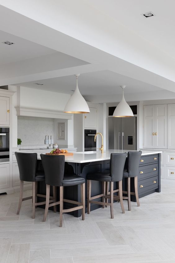 a large kitchen with an island and bar stools in the center, surrounded by white cabinets