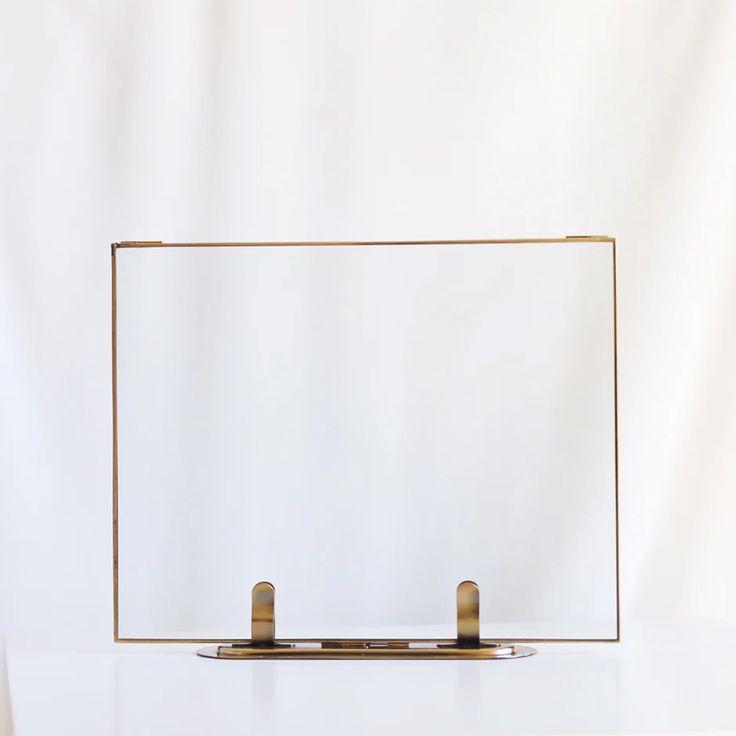 a white table with a gold frame and two small metal objects on top of it