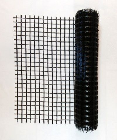 a piece of black wire mesh sitting on top of a white table next to a roll of yarn