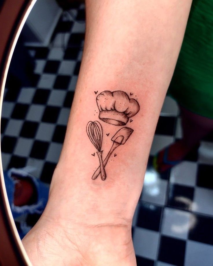 a person with a tattoo on their arm holding a spoon and whisk in it