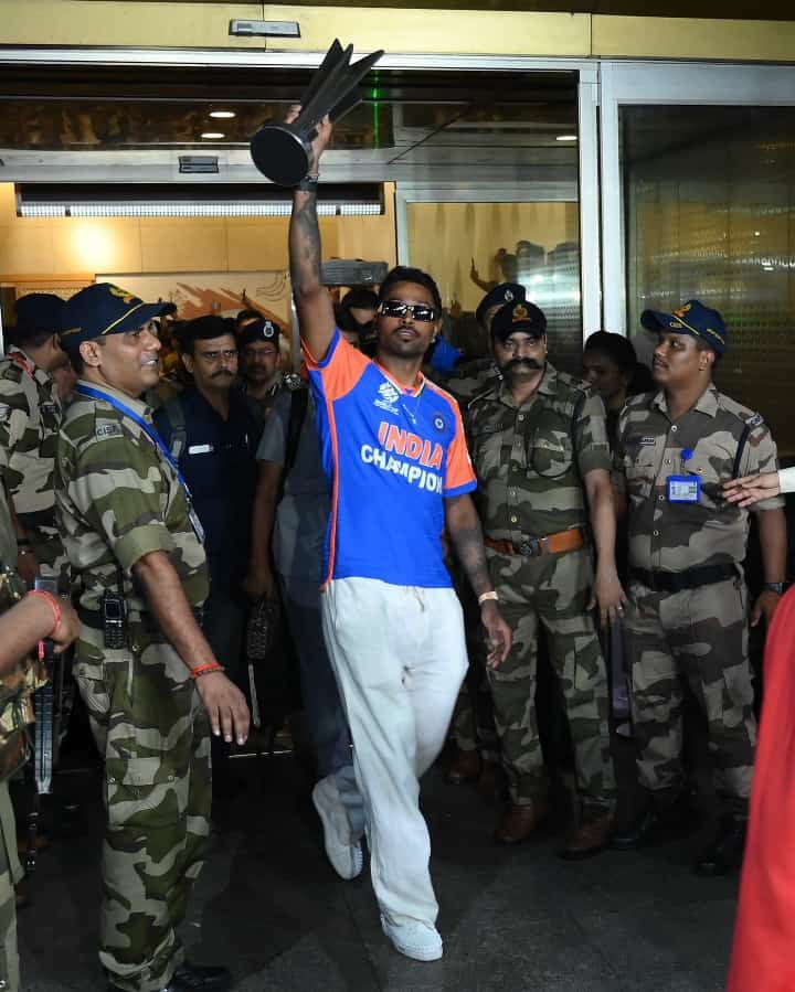 a man in blue shirt and white pants standing next to men in army uniforms holding something up