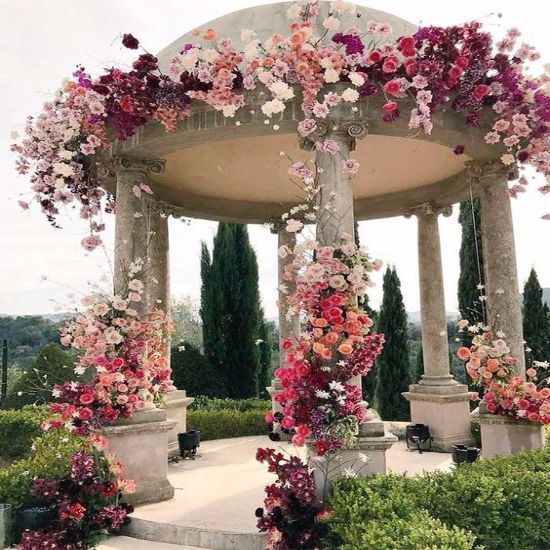 a gazebo covered in lots of pink and red flowers