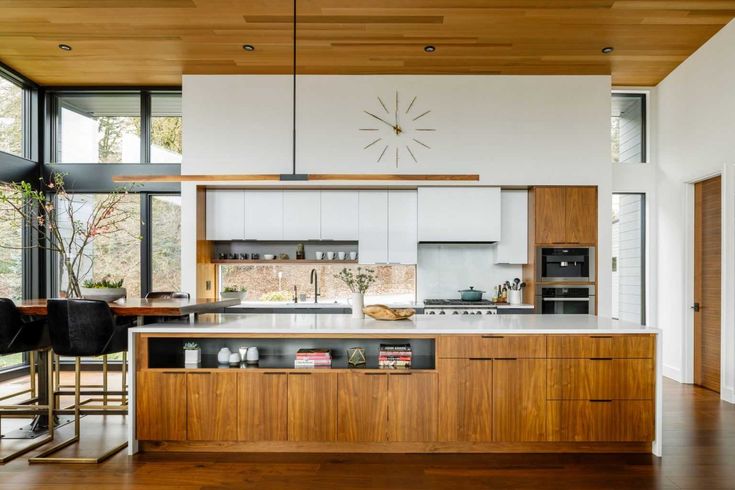 an open kitchen with wooden floors and white walls, along with lots of windows that look out onto the outdoors