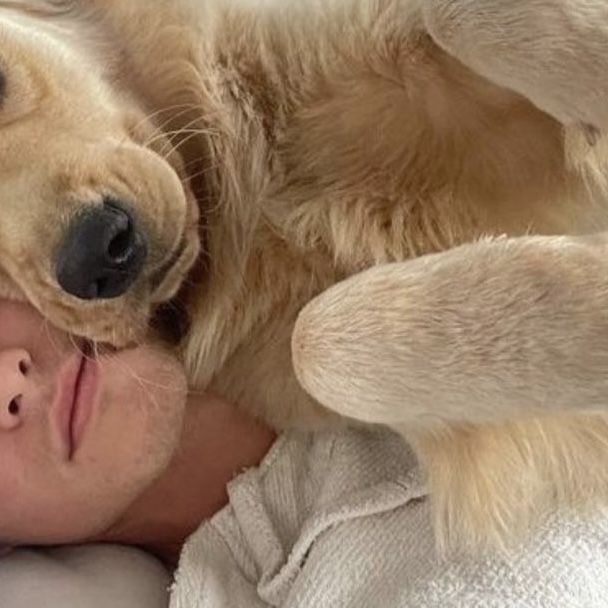 a woman laying on top of a dog with her head resting on the man's shoulder