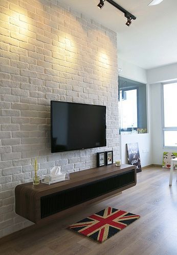 a flat screen tv mounted to the side of a brick wall in a living room