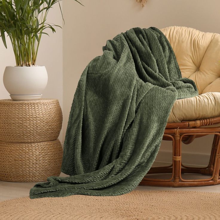 a chair with a blanket on it next to a potted plant