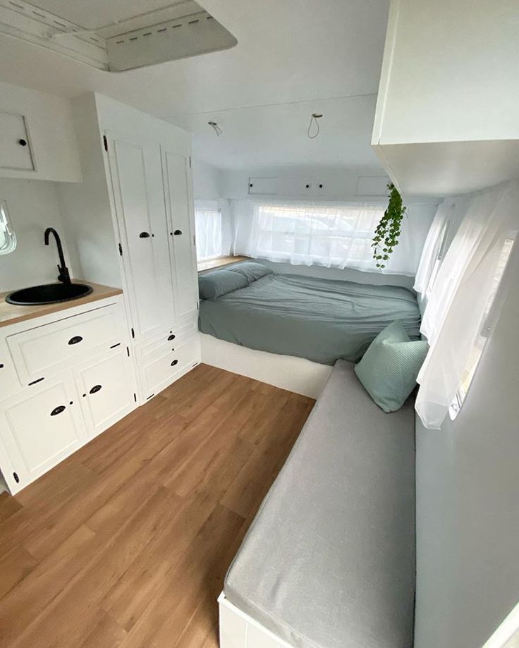 a bed sitting in the corner of a room next to a window and cupboards