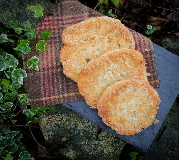 three biscuits sitting on top of a piece of cloth next to some green plants and rocks