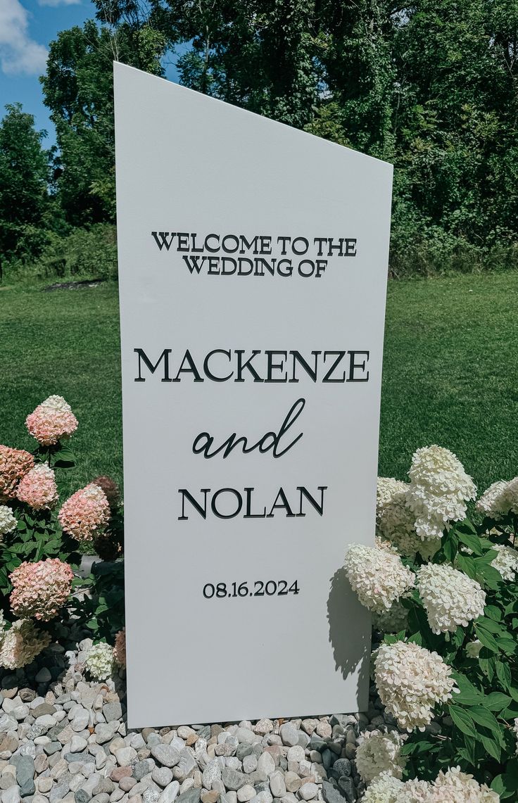 a welcome sign for the wedding of mackenze and nolan in front of flowers