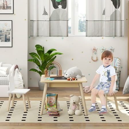 a little boy sitting on top of a wooden table next to a white chair in a living room