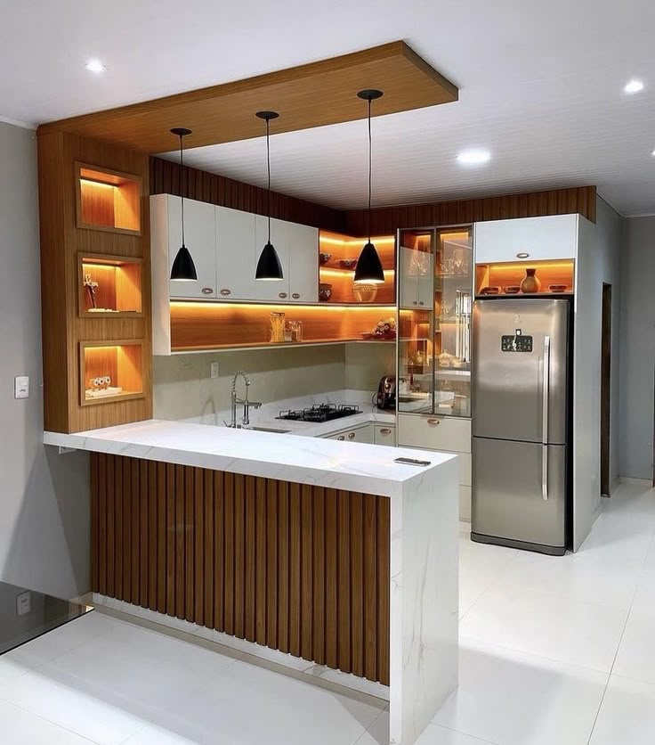 a modern kitchen with an island and stainless steel refrigerator freezer in the center, along with built - in lighting