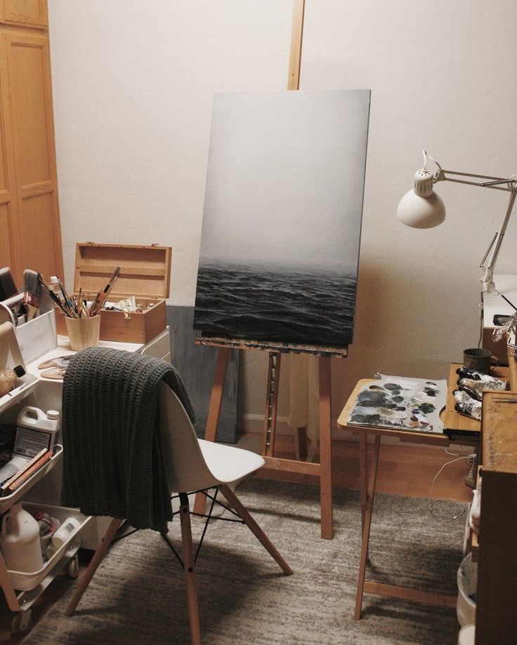 an artist's easel in front of a painting and other art supplies on the floor