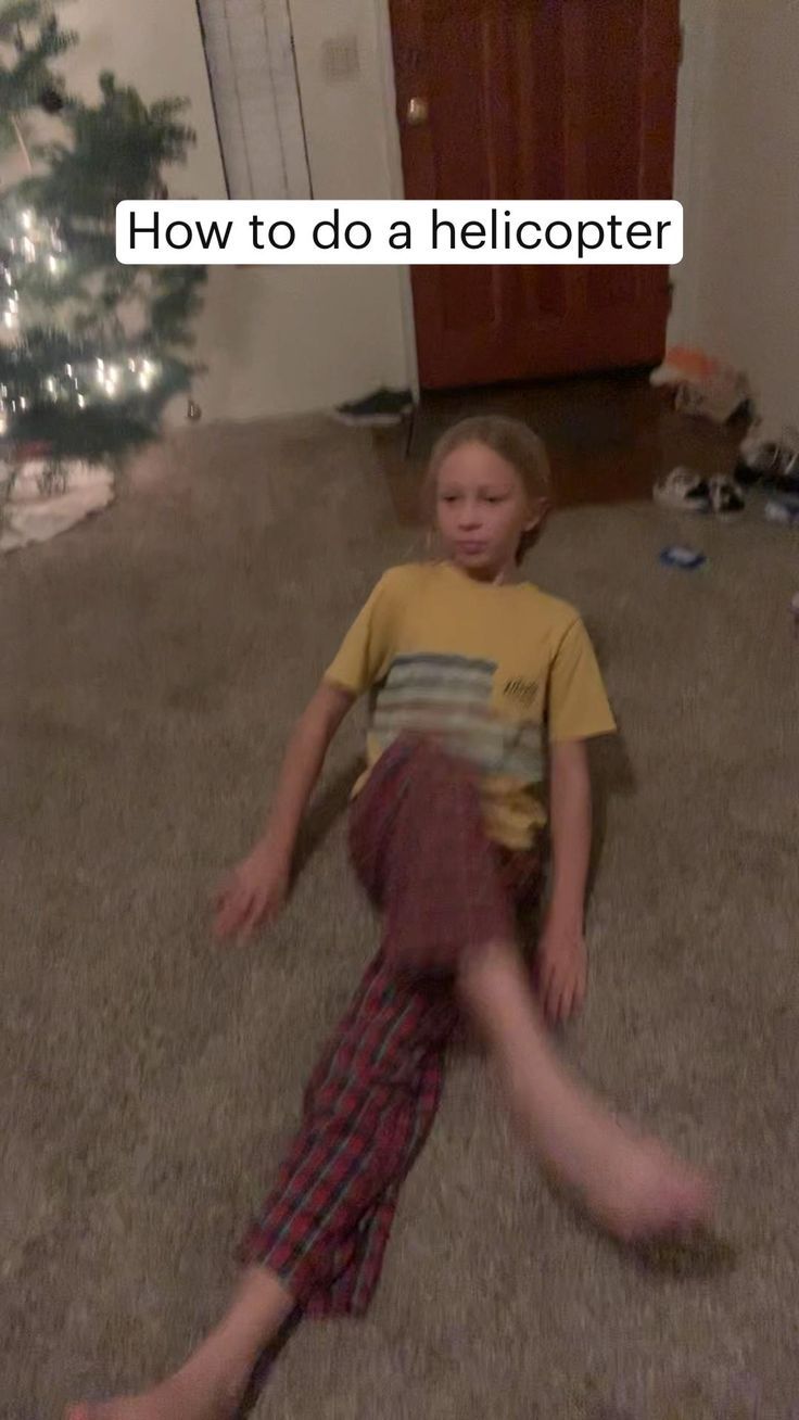 a young boy laying on the floor in front of a christmas tree with his legs spread out