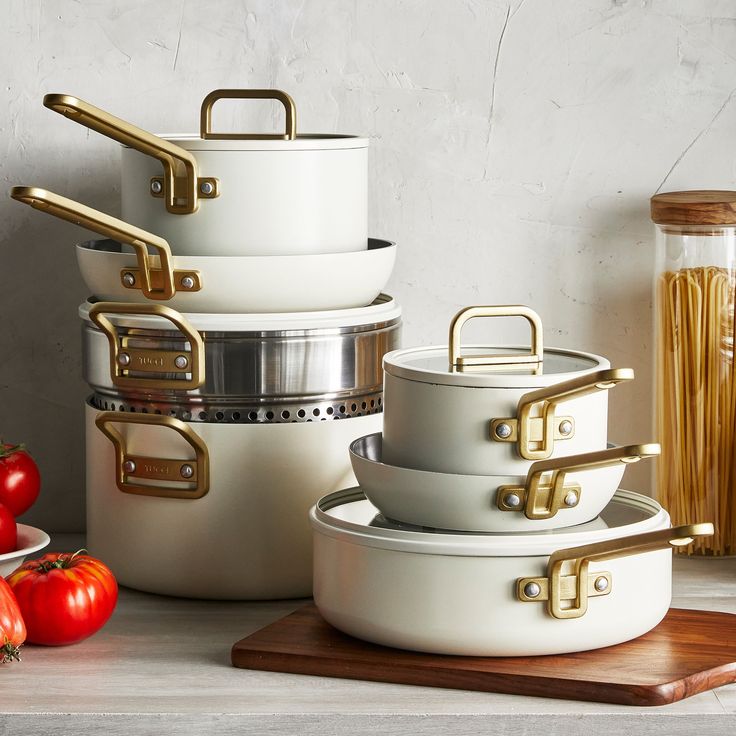 pots and pans are stacked on top of each other, with tomatoes in the background