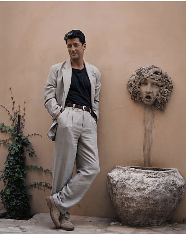 a man leaning against a wall next to a planter with a face on it