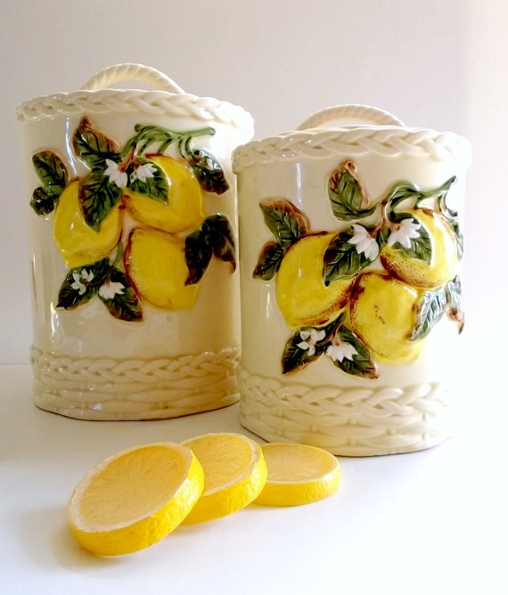 two glass jars with lemons and leaves on them