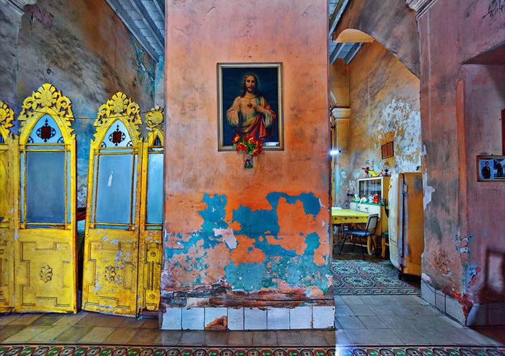 an old building with peeling paint on the walls and doors painted yellow, red, and blue