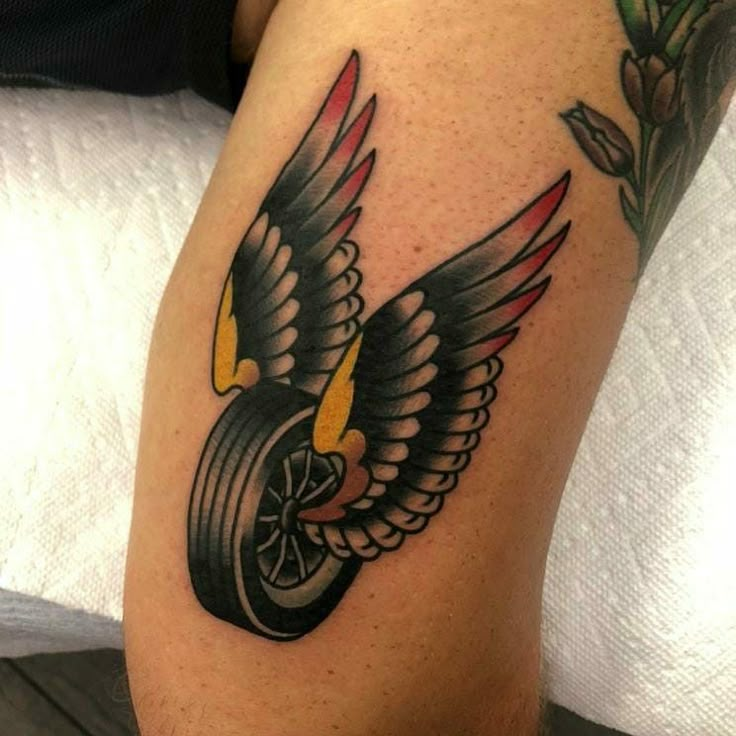 a tattoo on the leg of a man with an eagle and tire wheel in it