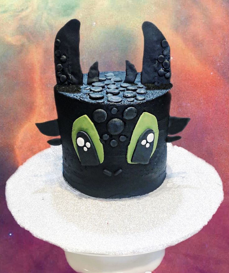 a cake decorated with black icing and green eyes