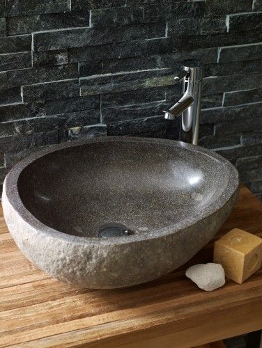 a stone bowl sink sitting on top of a wooden counter