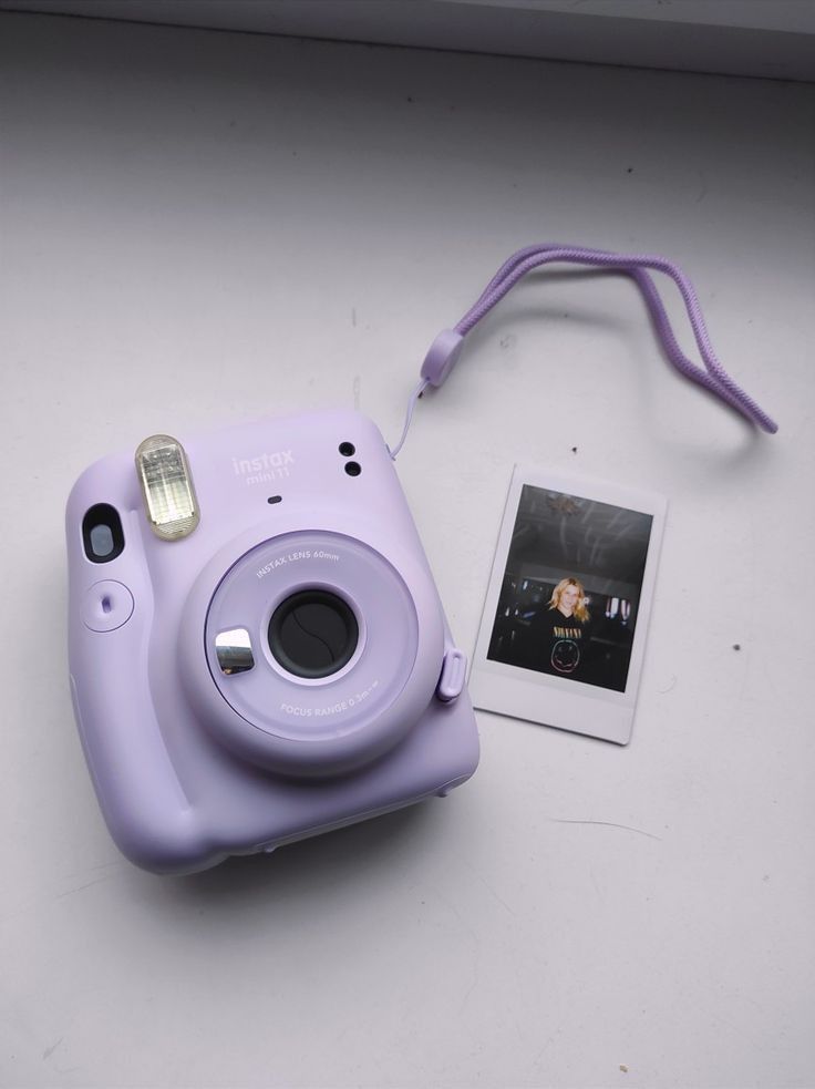 a purple camera sitting on top of a white table next to a small photo album