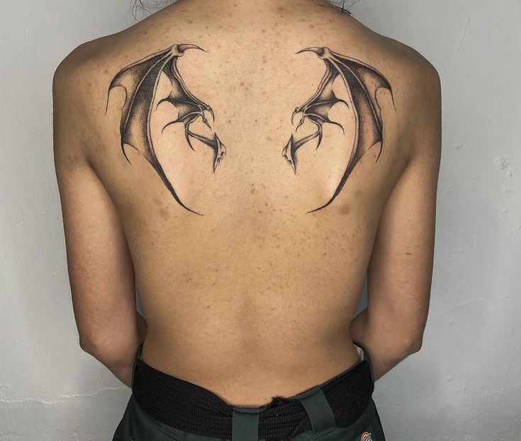 the back of a woman's neck with two dragon tattoos on her upper and lower back