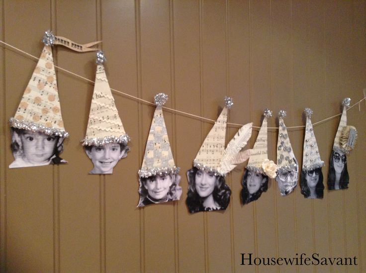 several hats are hanging on a string with pictures attached to them and pinned to the wall