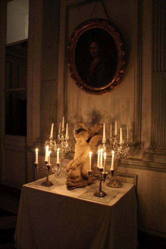 a table topped with lots of candles next to a painting