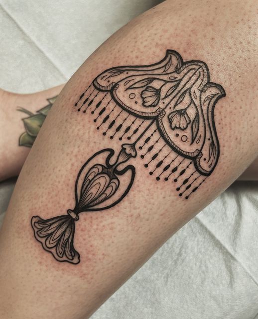 a tattoo on the leg of a woman with scissors and hair combs attached to it