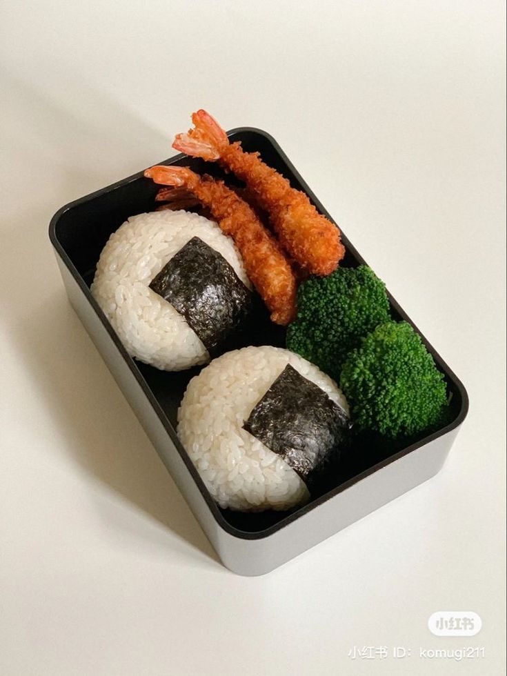 sushi with shrimp, broccoli and carrots in a plastic container on a white surface